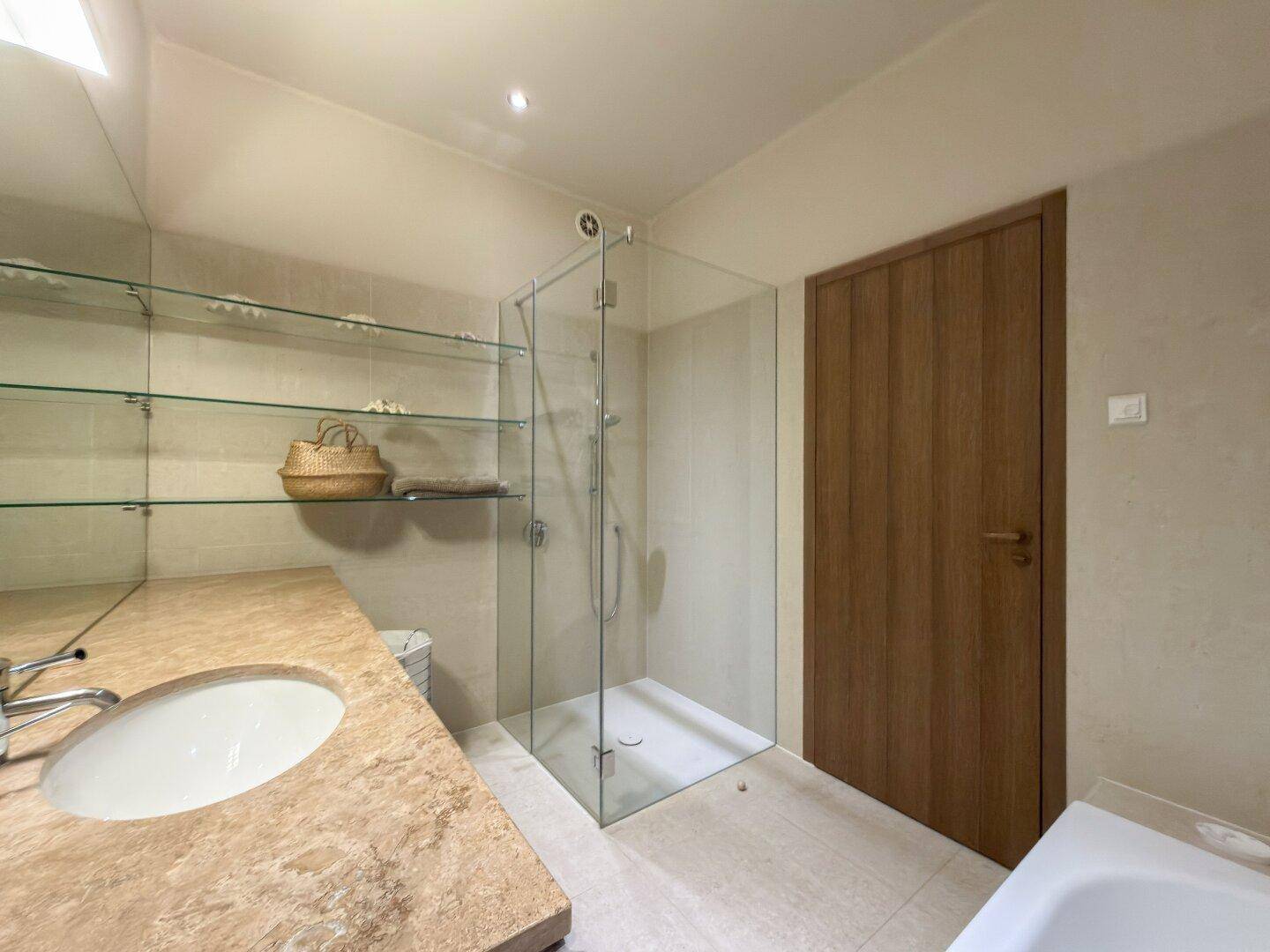 Modernes Badezimmer mit begehbarer Dusche, Waschbecken und Glasregalen für Ablage.