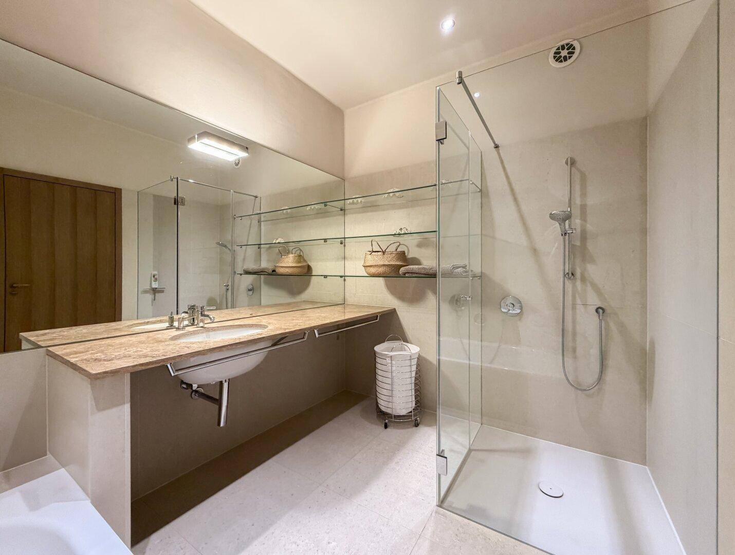 Modernes Badezimmer mit begehbarer Dusche, Waschbecken und großem Spiegel.