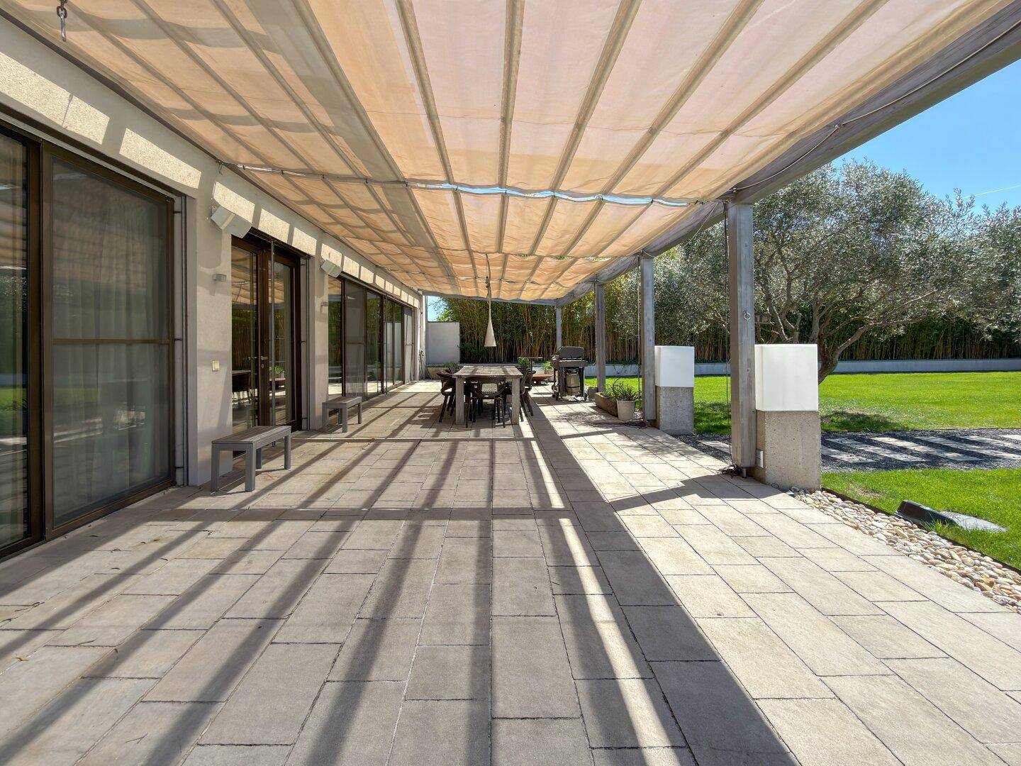 Geräumige überdachte Terrasse mit großem Esstisch, Grillbereich und Zugang zum Garten.