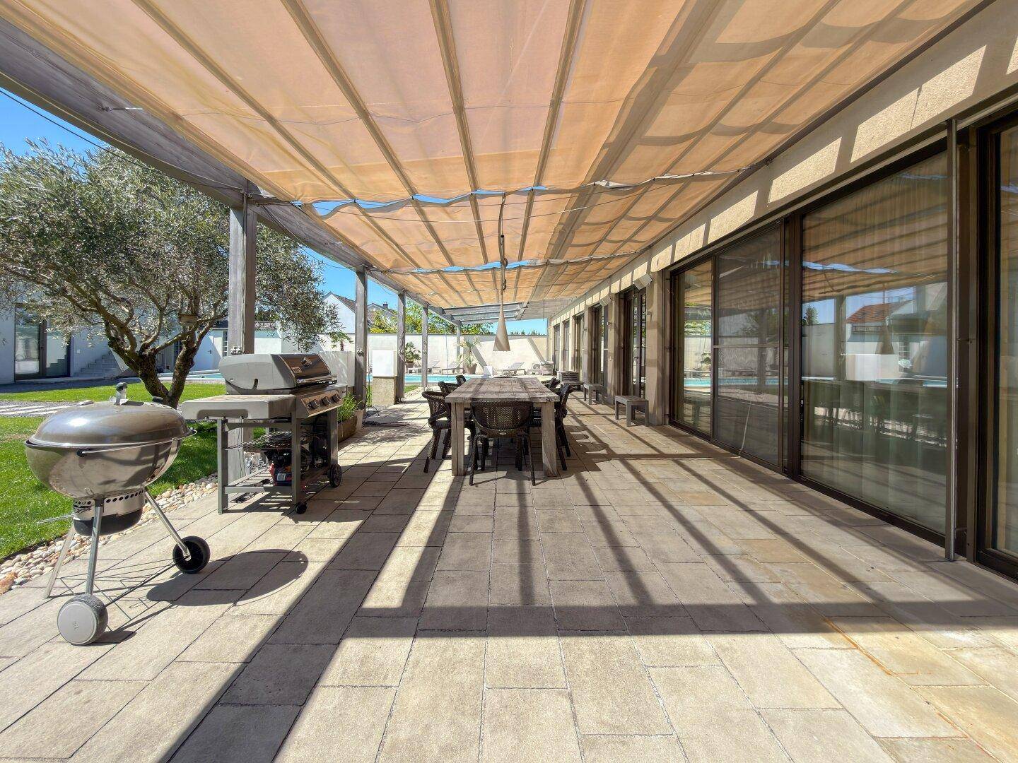 Weitläufige Terrasse mit Essbereich und Grill, direkt am Haus mit Blick auf den Pool.