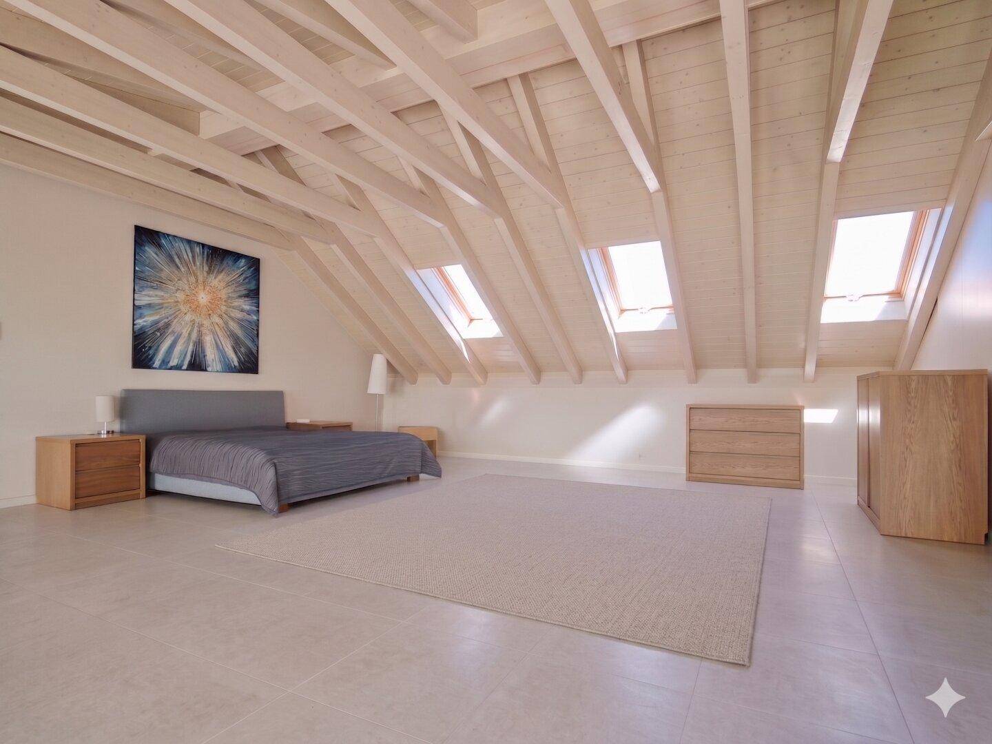 Helles Schlafzimmer im Dachgeschoss mit Dachfenstern, Holzbalken und modernem Bett.