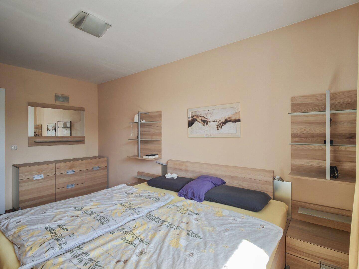 Helles Schlafzimmer mit Doppelbett, Holzmöbeln und viel Stauraum durch Kommoden.