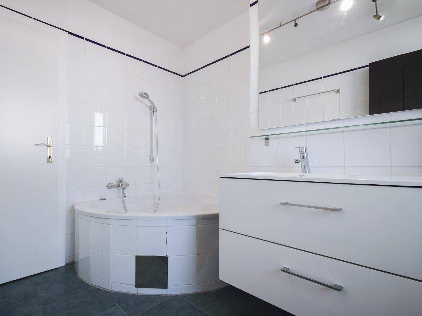 Modern gefliestes Badezimmer mit Eckbadewanne, Duschfunktion und Einzelwaschbecken.