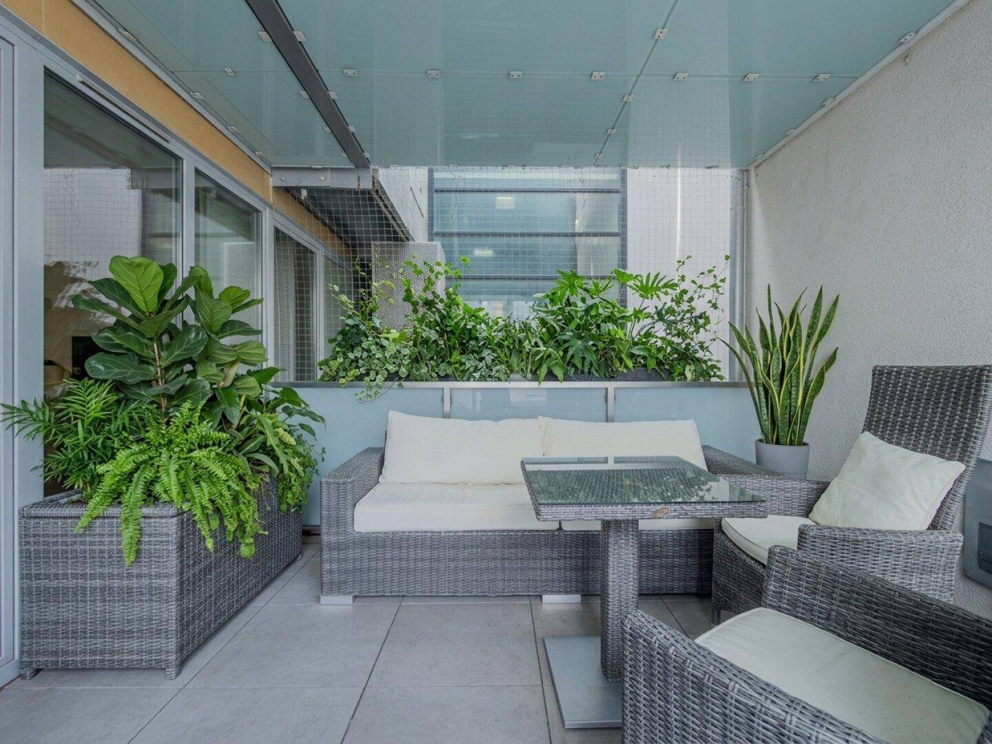Überdachter Balkon mit bequemen Outdoor-Möbeln und Pflanzen, ideal zum Entspannen.