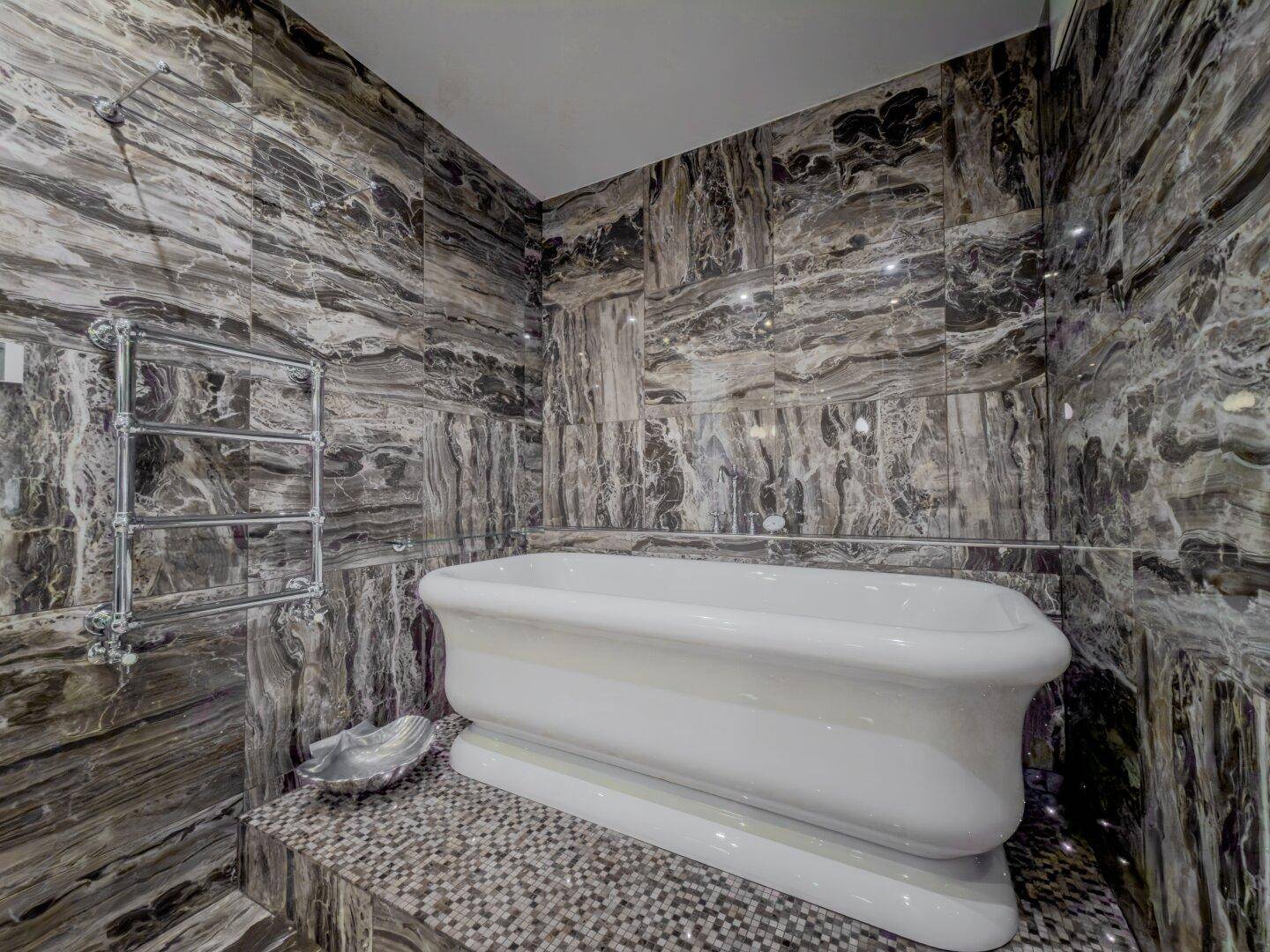 Elegantes Badezimmer mit dunklen Marmorfliesen und einer freistehenden Badewanne.