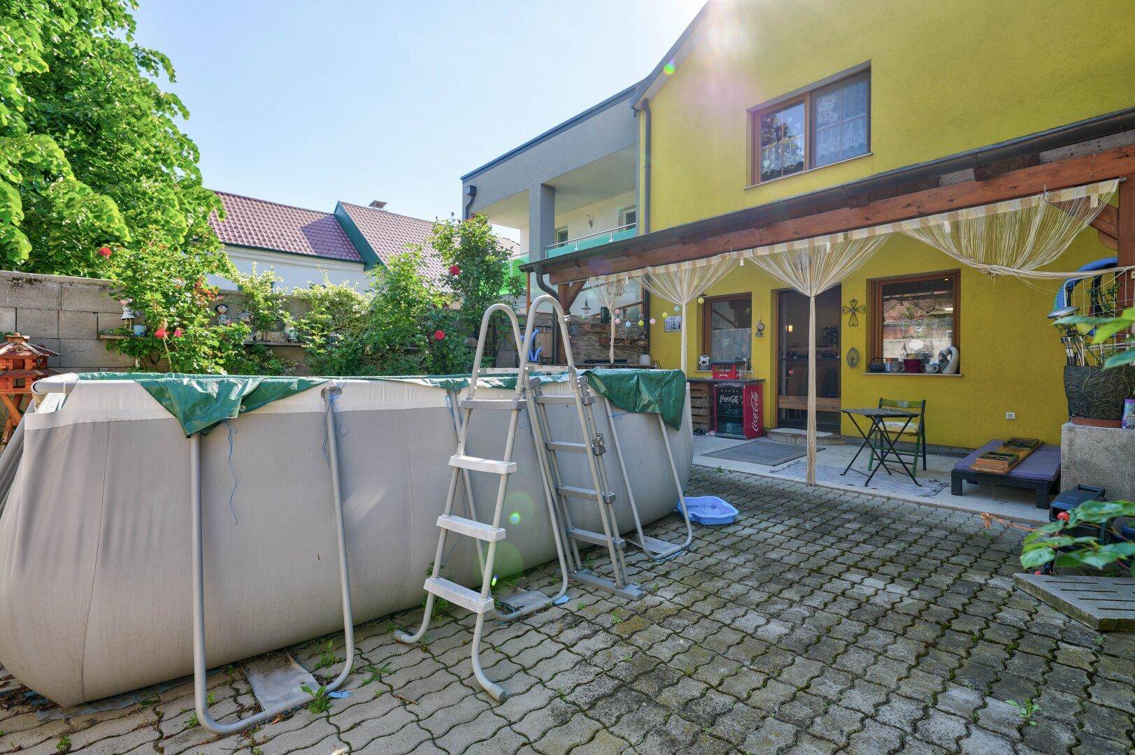 Hinterhof mit großem Aufstellpool, überdachtem Bereich und Zugang zum Haus.
