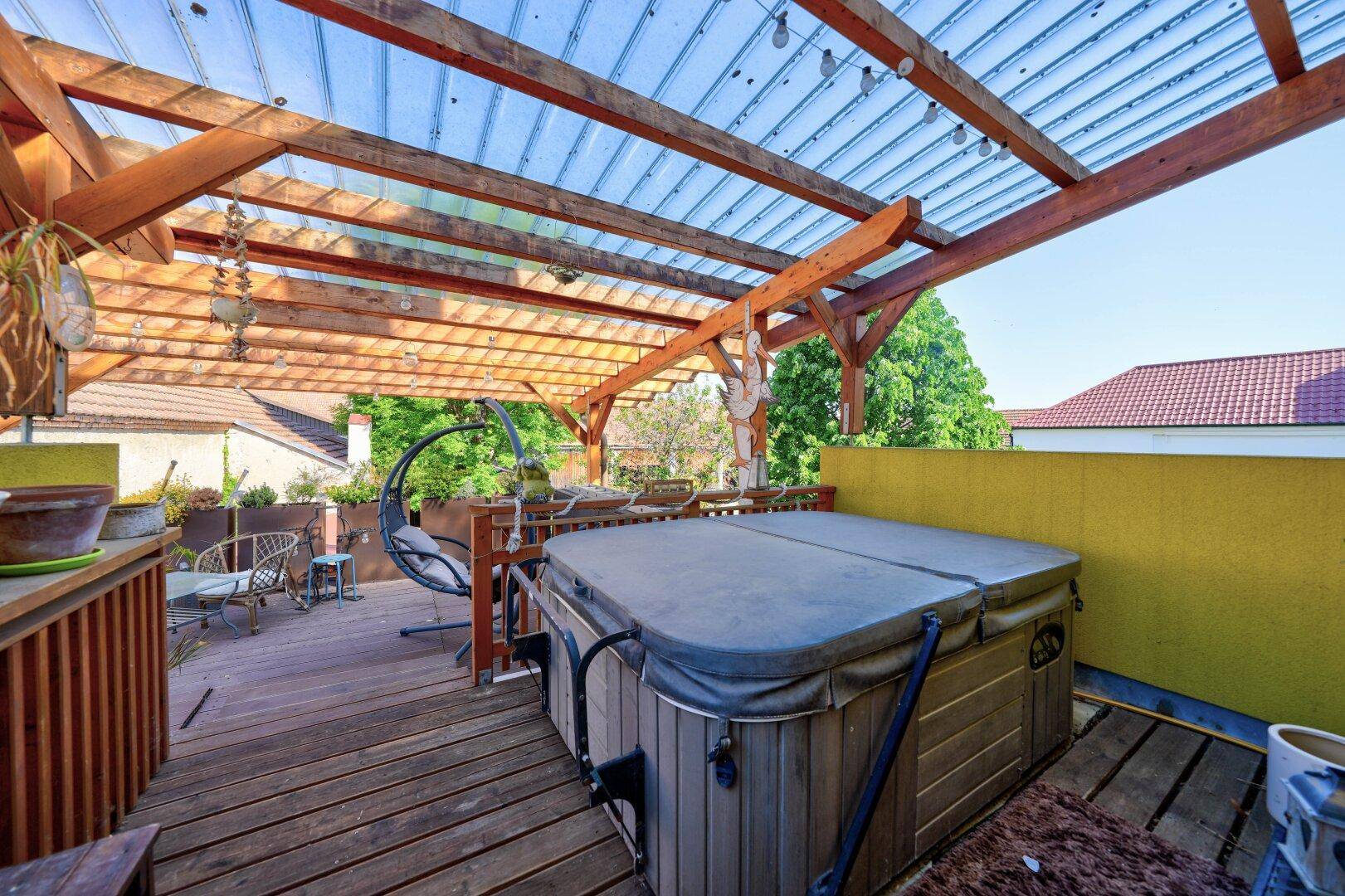 Große Dachterrasse mit Whirlpool, Holzpergola und Sitzgelegenheiten.