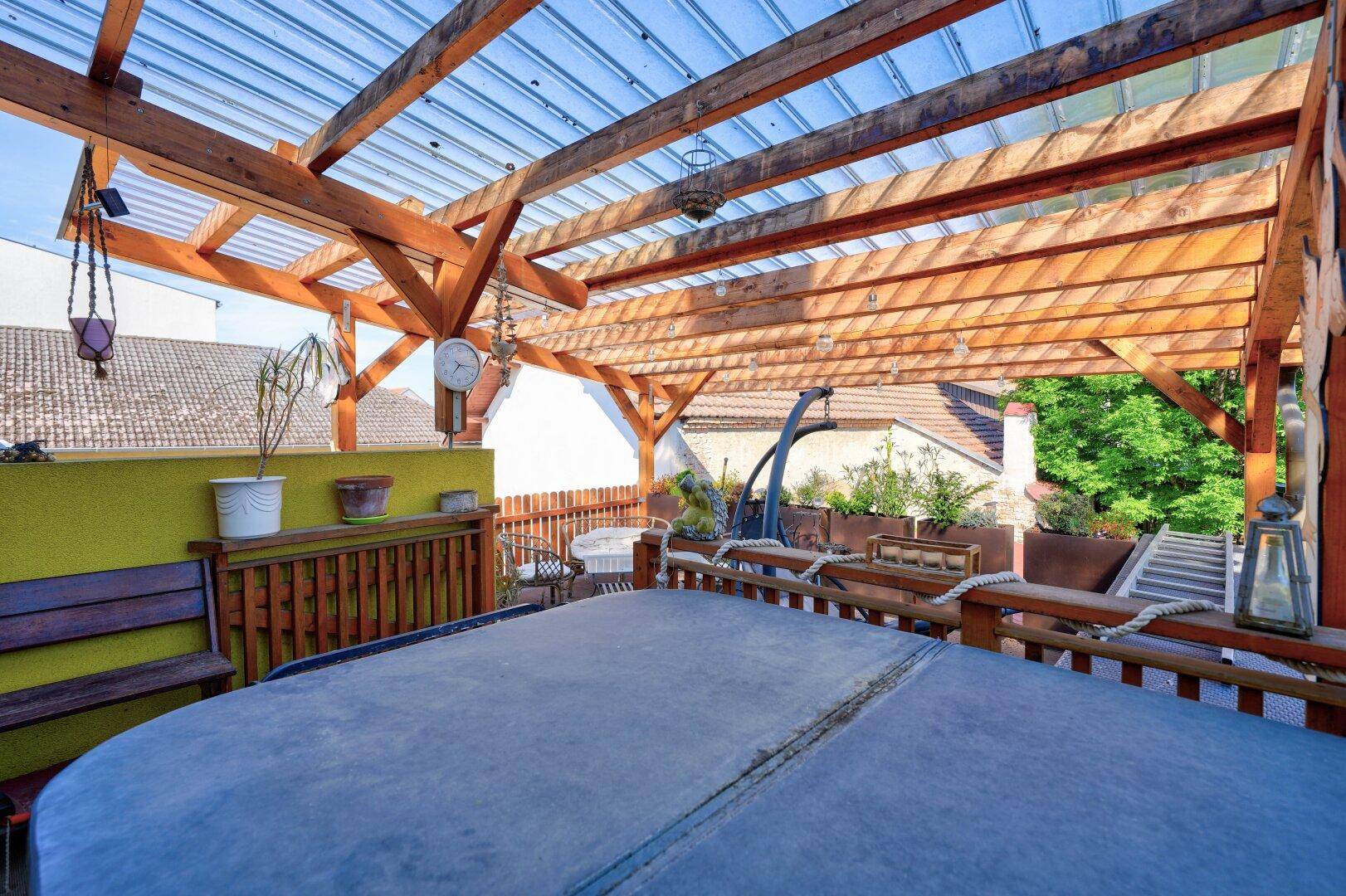 Sonnenterrasse mit Holzpergola, Whirlpool und weitem Blick über die Umgebung.