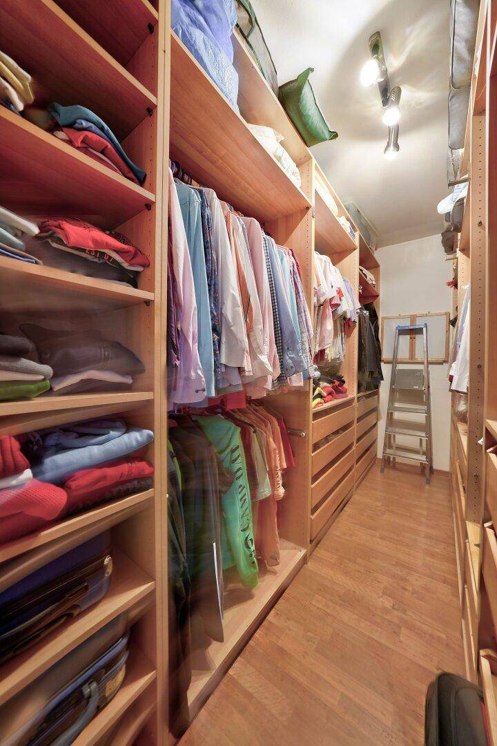 Geräumiger begehbarer Kleiderschrank mit vielen Holzregalen und Stauraum.