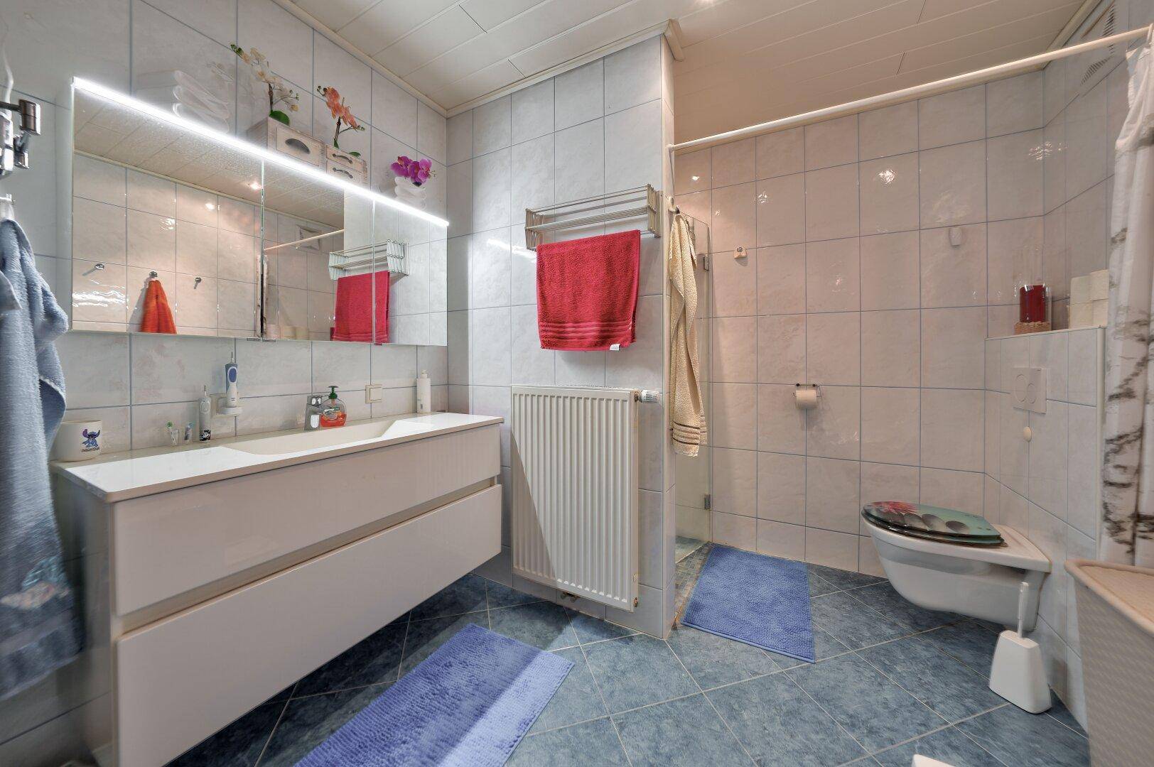 Helles Badezimmer mit großem Waschtisch, Spiegel und Badewanne.
