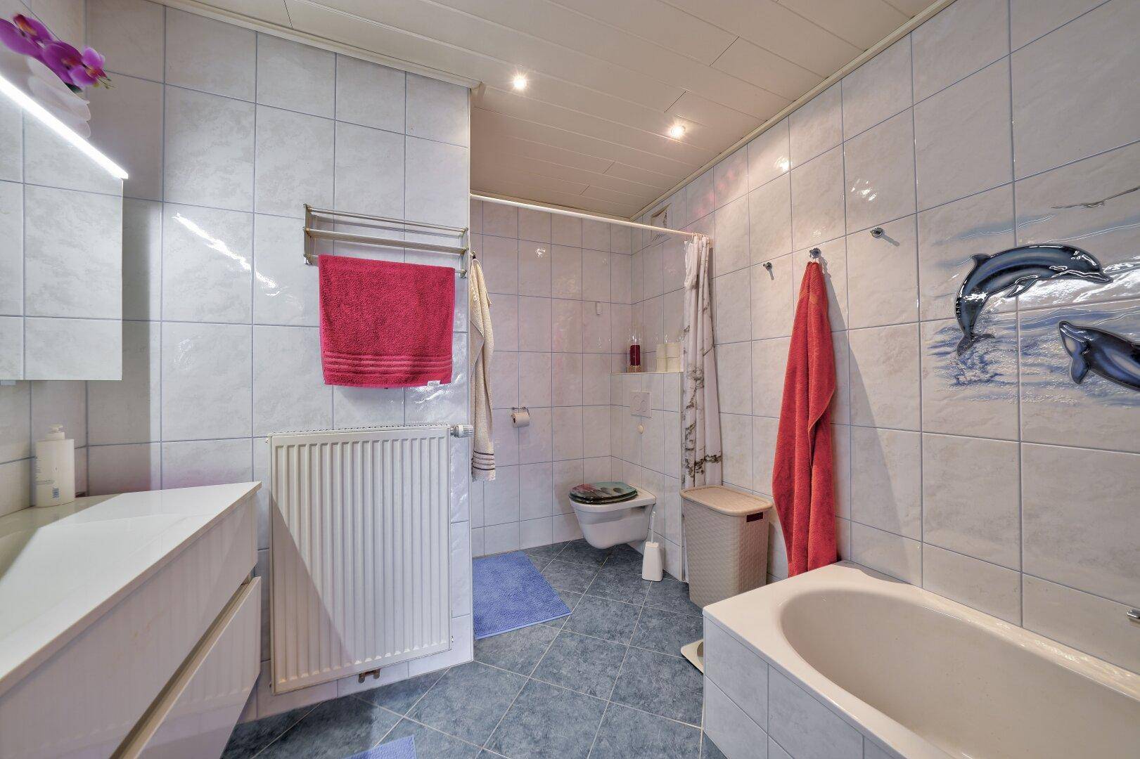 Gefliestes Badezimmer mit Badewanne, Dusche und WC in hellen Farben.