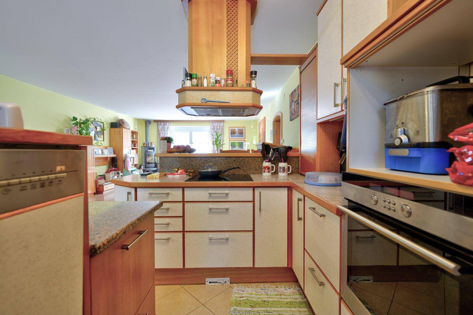 Funktionale Küche mit Holzfronten, Granitarbeitsplatte und Blick in den Wohnbereich.