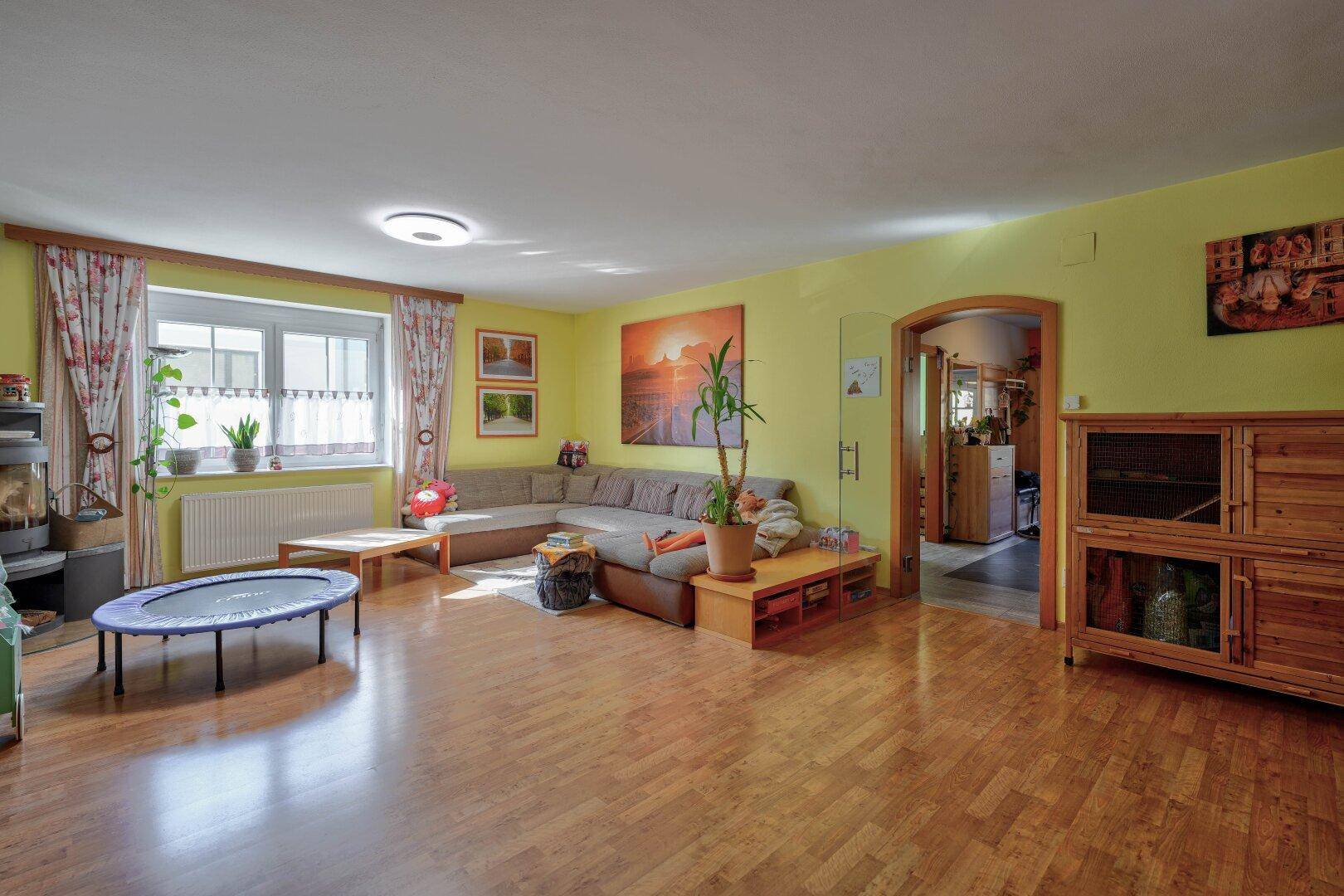 Geräumiges Wohnzimmer mit Sofa, Holzboden und großem Fenster für viel Licht.
