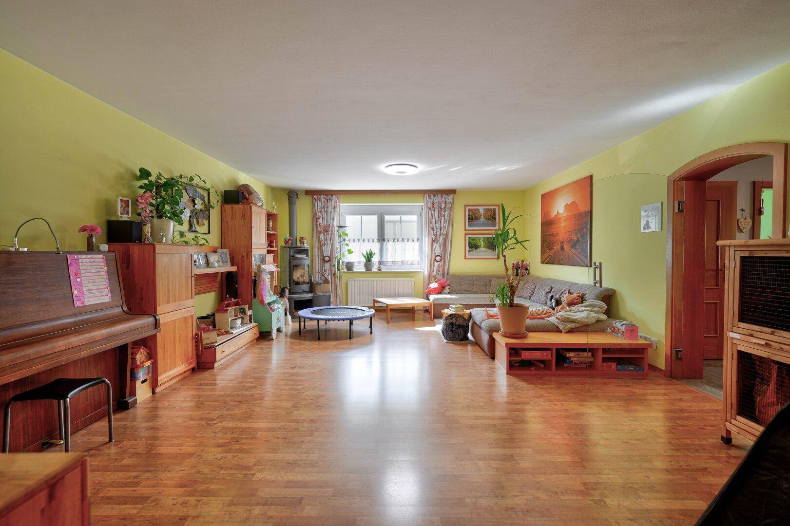 Gemütliches Wohnzimmer mit Sofa, Holzboden und Blick auf den Garten.