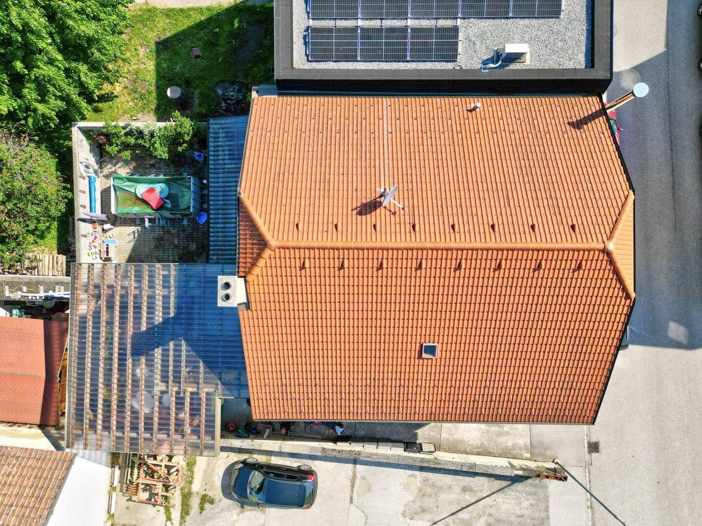 Draufsicht auf das Haus mit rotem Ziegeldach und angrenzendem überdachtem Bereich.