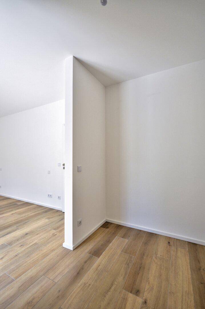 Heller, leerer Raum mit Holzboden und weißen Wänden, bereit für die Einrichtung.
