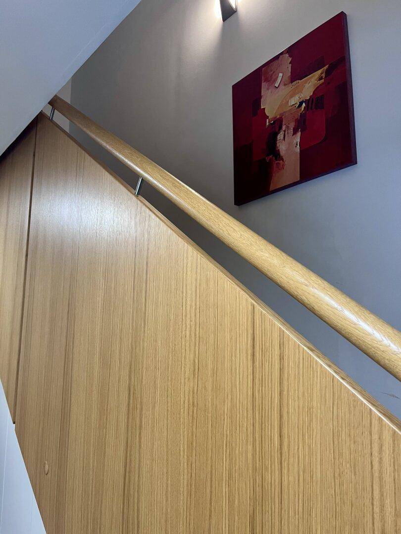 Holztreppe mit modernem Geländer und Kunst an der Wand.