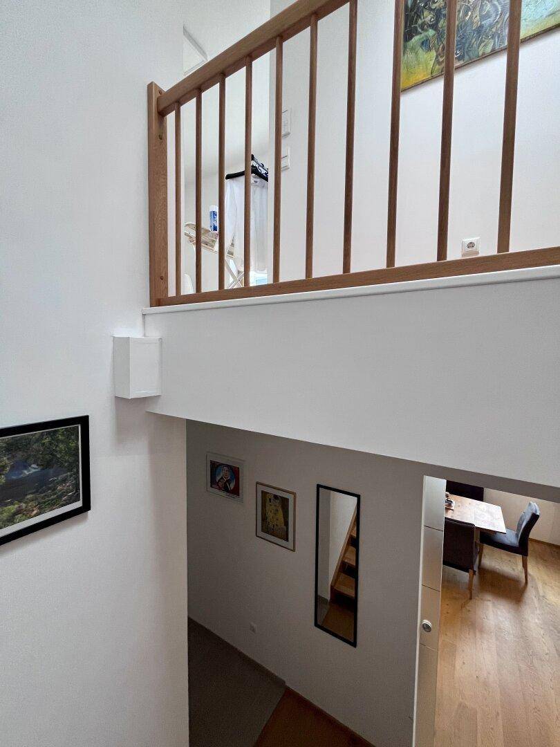Heller Flur mit Holzgeländer und Blick auf die untere Etage.