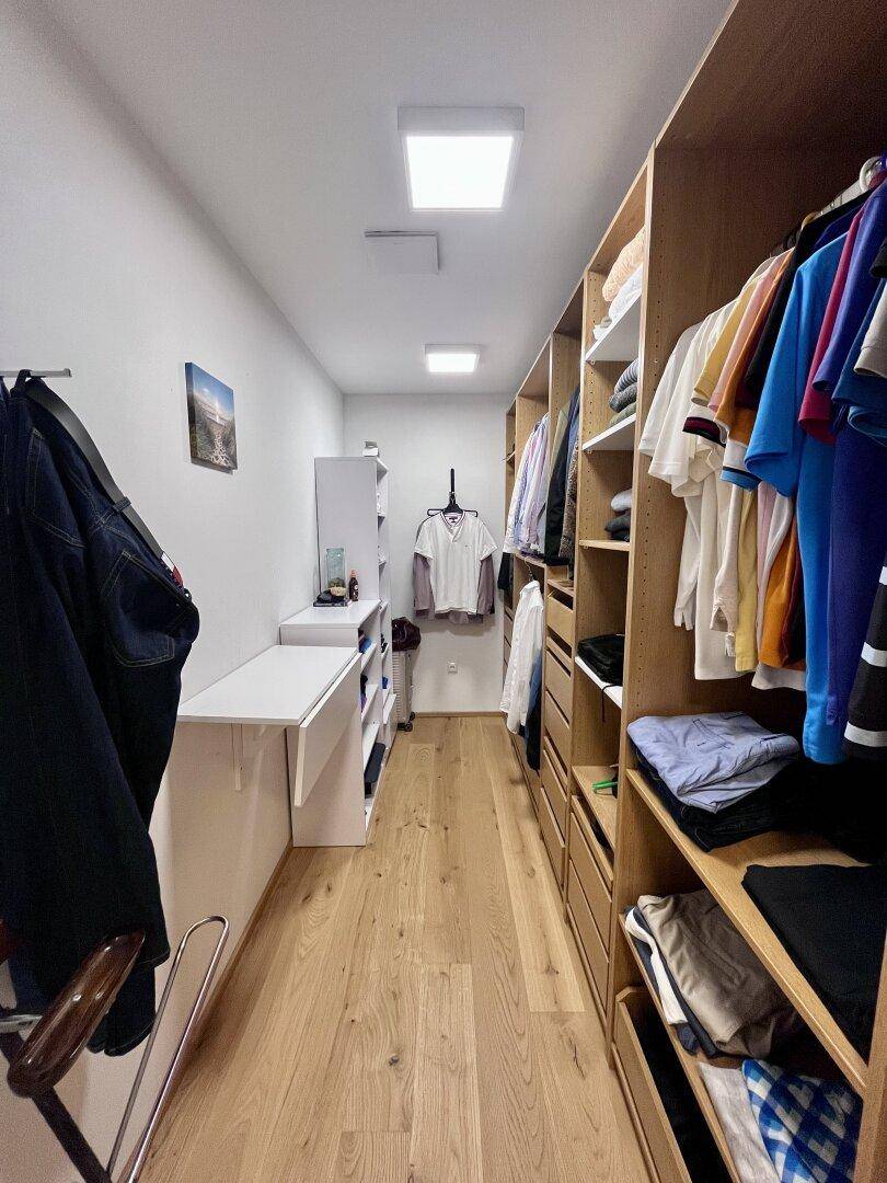 Geräumiger begehbarer Kleiderschrank mit viel Stauraum und Holzboden.