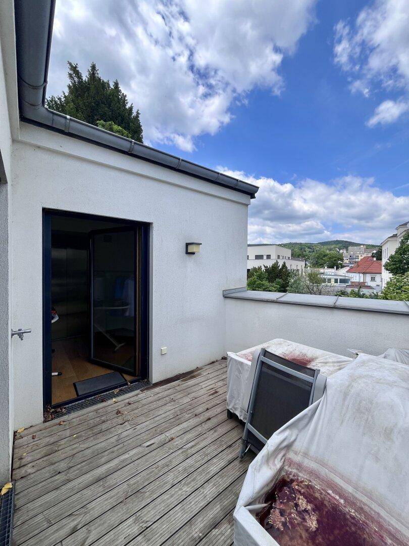Dachterrasse mit Holzbelag, Gartenmöbeln und Blick auf die Umgebung.