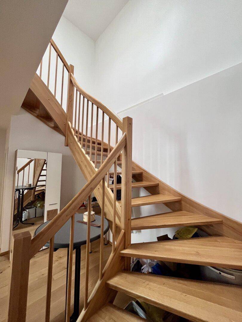Elegante Holztreppe mit geschwungenem Geländer, die die Etagen verbindet.