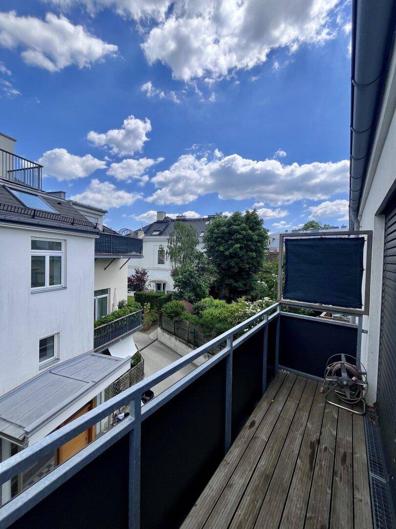 Balkon mit Holzbelag und Geländer, bietet einen Blick auf die Nachbarschaft.