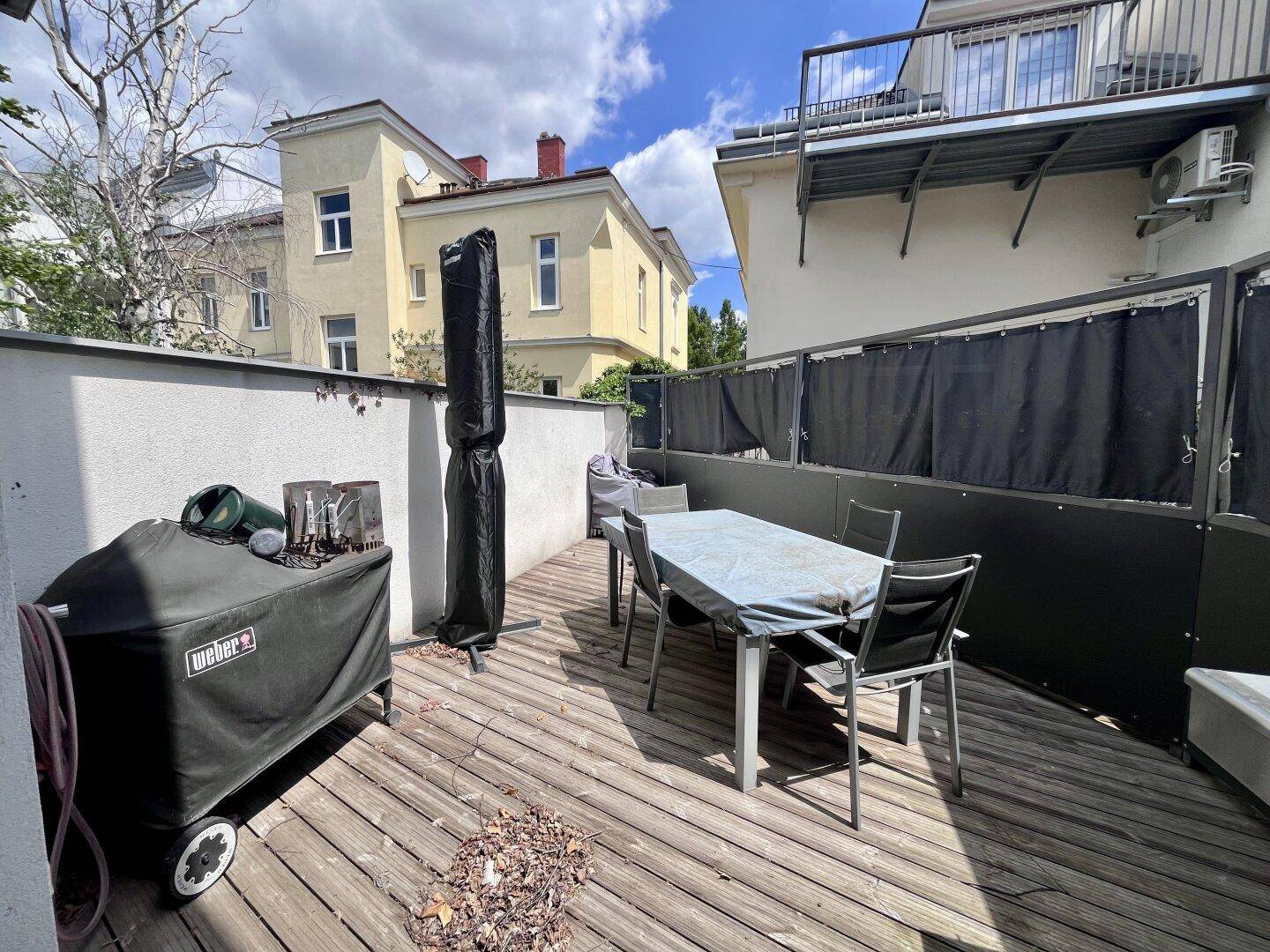 Geräumige Holzterrasse mit Grillbereich und Esstisch, ideal für Mahlzeiten im Freien.