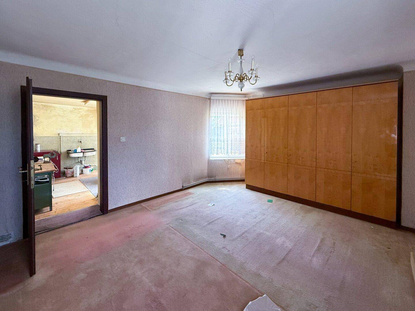 Leeres Zimmer mit Teppichboden und Einbauschrank, das auf eine Modernisierung wartet.