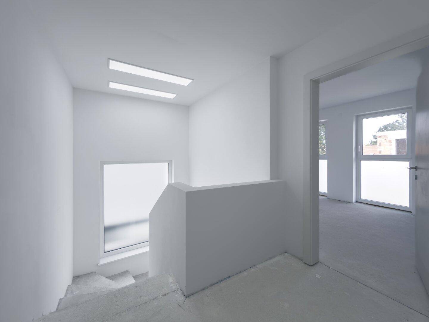 Heller Treppenaufgang mit modernen Fenstern und minimalistischem Design.