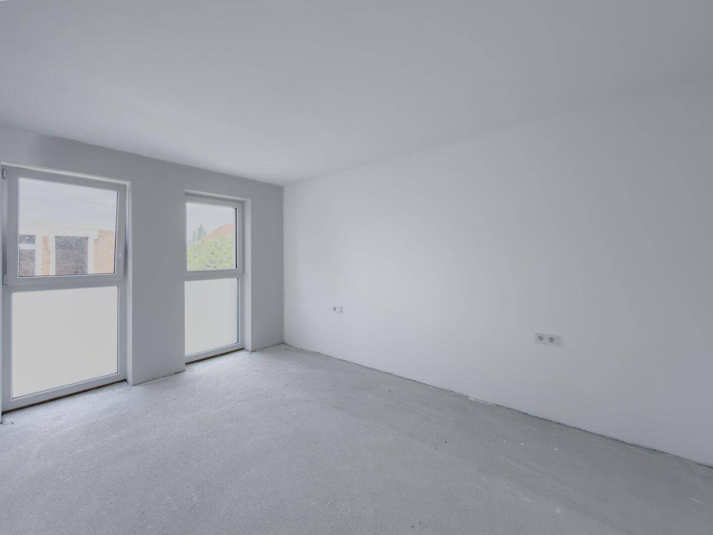 Unfertiges Schlafzimmer mit zwei großen Fenstern, die viel Tageslicht hereinlassen.