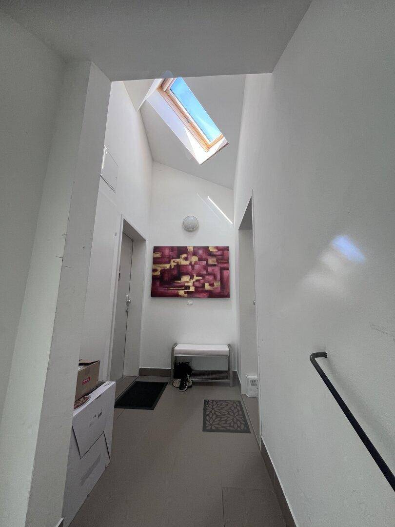 Heller Flur mit einem Dachfenster, das viel natürliches Licht hereinlässt, und moderner Dekoration.