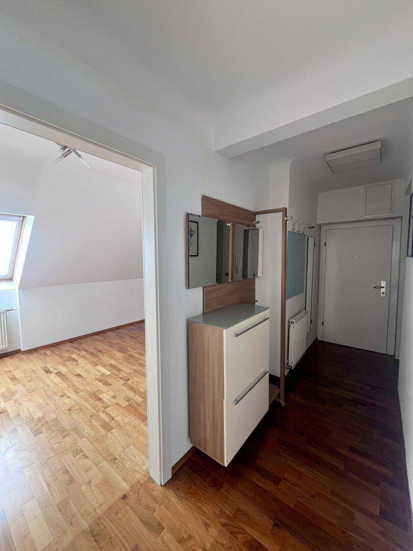 Heller Flur mit Garderobe, Schuhschrank und Zugang zu einem weiteren Zimmer im Dachgeschoss.