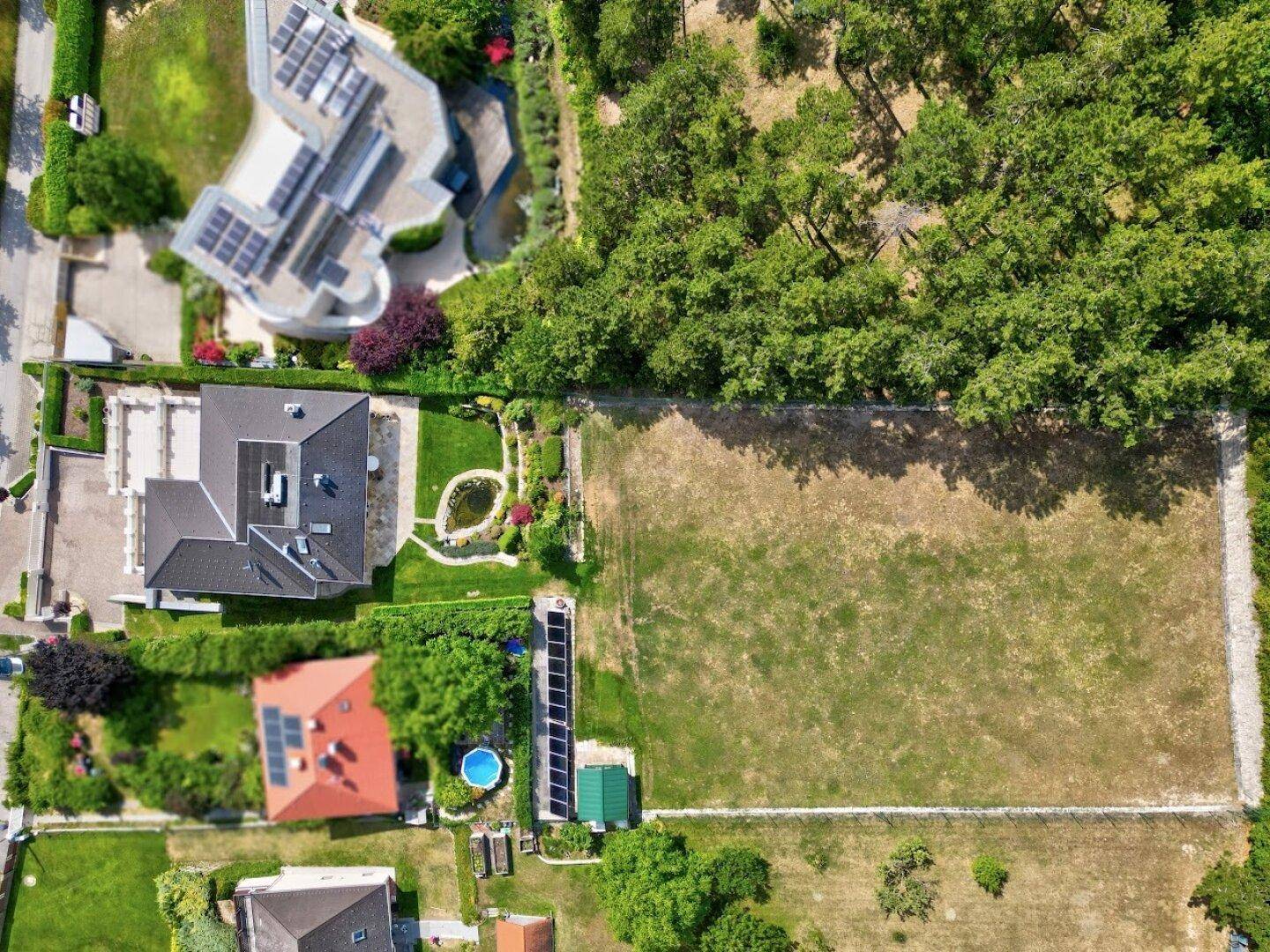 Luftaufnahme eines weitläufigen Anwesens mit großem Grundstück, Garten und angrenzendem Waldgebiet.