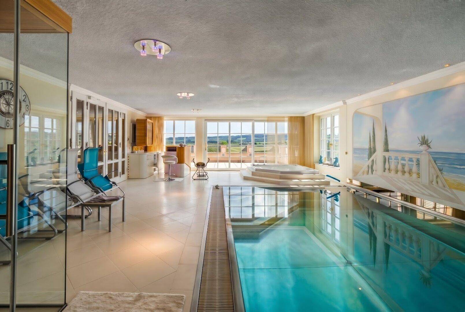 Großzügiger Innenpoolbereich mit Wellness-Oase, großen Fenstern und weitem Ausblick in die Landschaft.