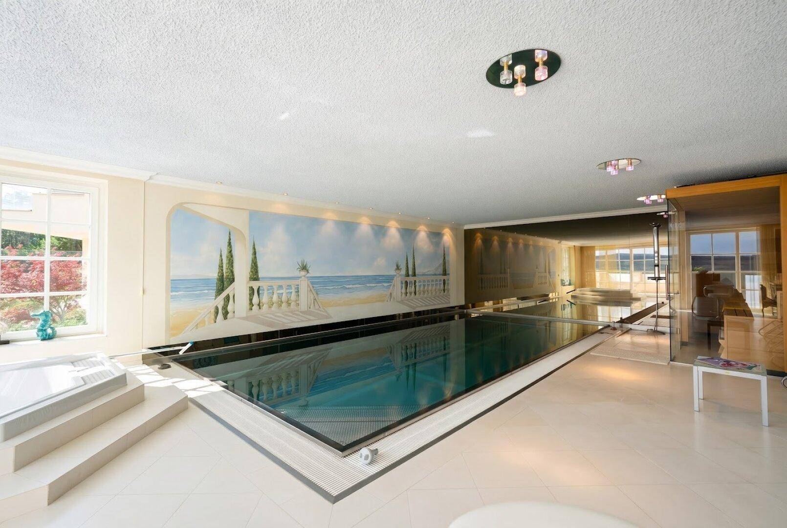 Luxuriöser Innenpool mit Wandgemälde und großzügiger Gestaltung, ideal für Entspannung und Sport.