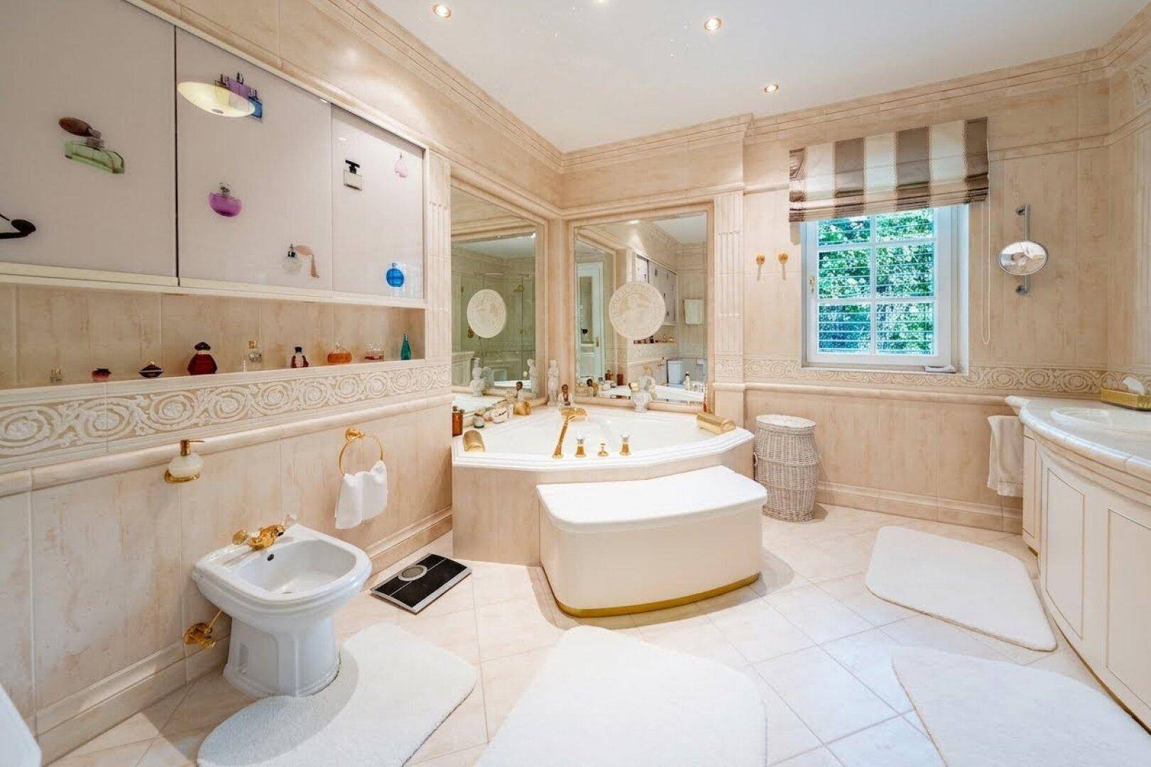 Luxuriöses Badezimmer mit Eckbadewanne, Bidet und eleganten Marmorfliesen in hellem Design.