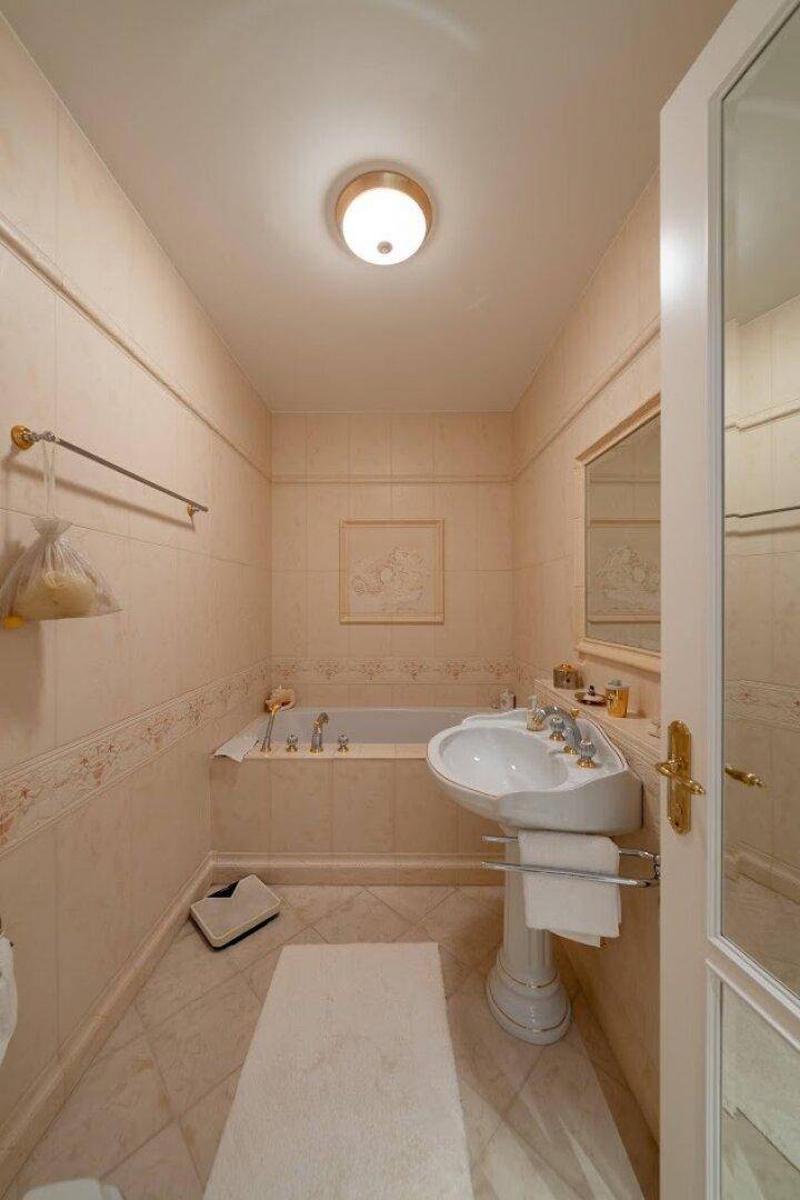 Klassisches Badezimmer mit Badewanne, Waschtisch und hellen Fliesen, in gutem Zustand.