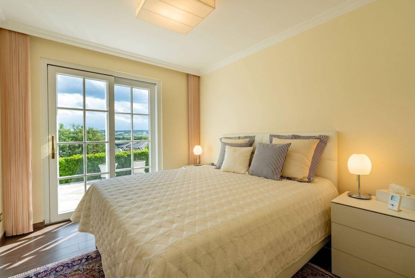 Gemütliches Schlafzimmer mit Doppelbett und direktem Zugang zu einem Balkon mit Ausblick.