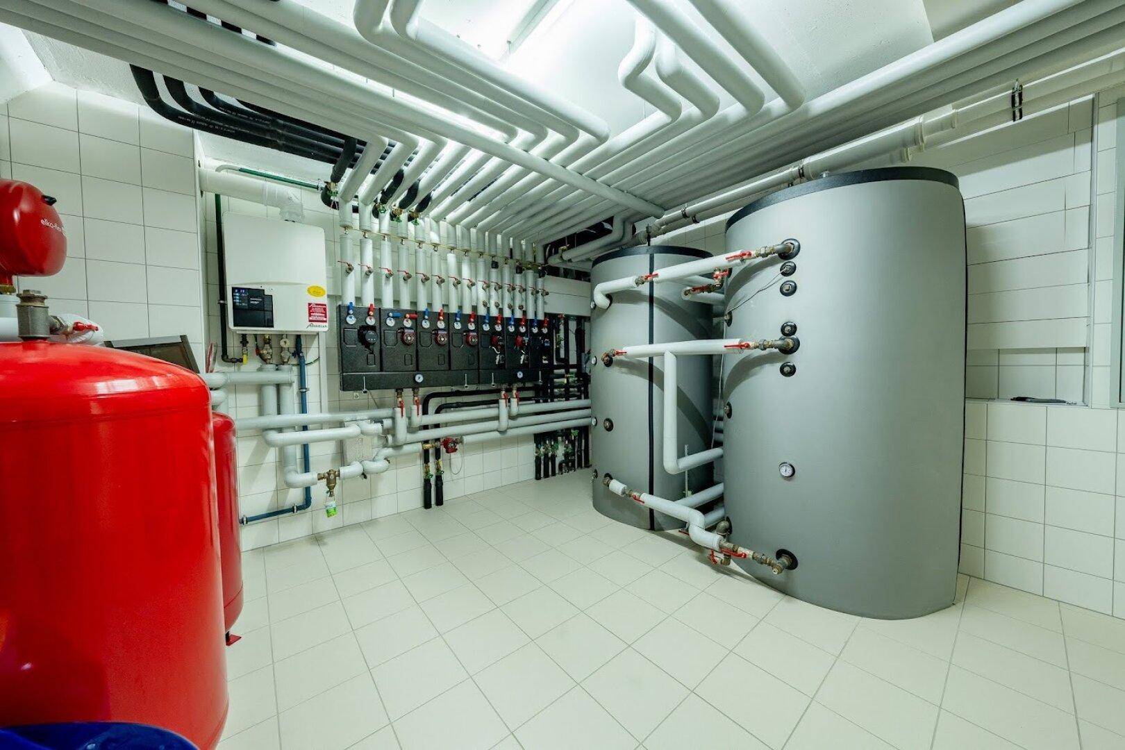 Heizungsraum mit modernen Warmwasserspeichern und umfangreicher Rohrinstallation.