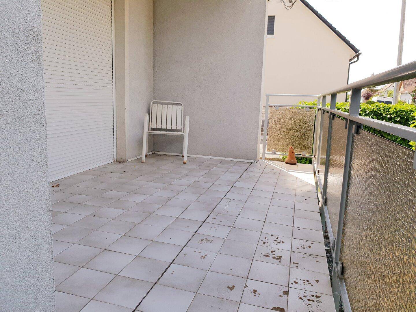 Helles, gefliestes Balkon mit einfacher Bestuhlung und Blick auf die Umgebung.
