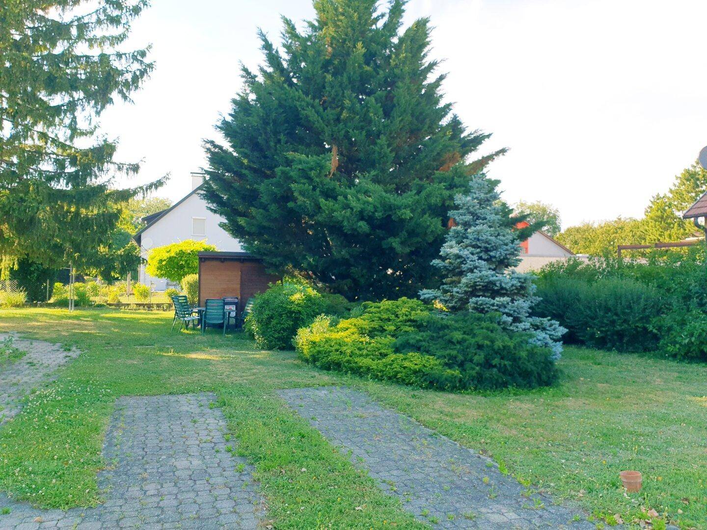 Großer Gartenbereich mit altem Baumbestand, Rasenfläche und einem kleinen Gartenhaus.