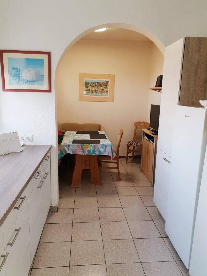 Essbereich in der Küche mit einem Holztisch und Sitzbank, verbunden durch einen Rundbogen.