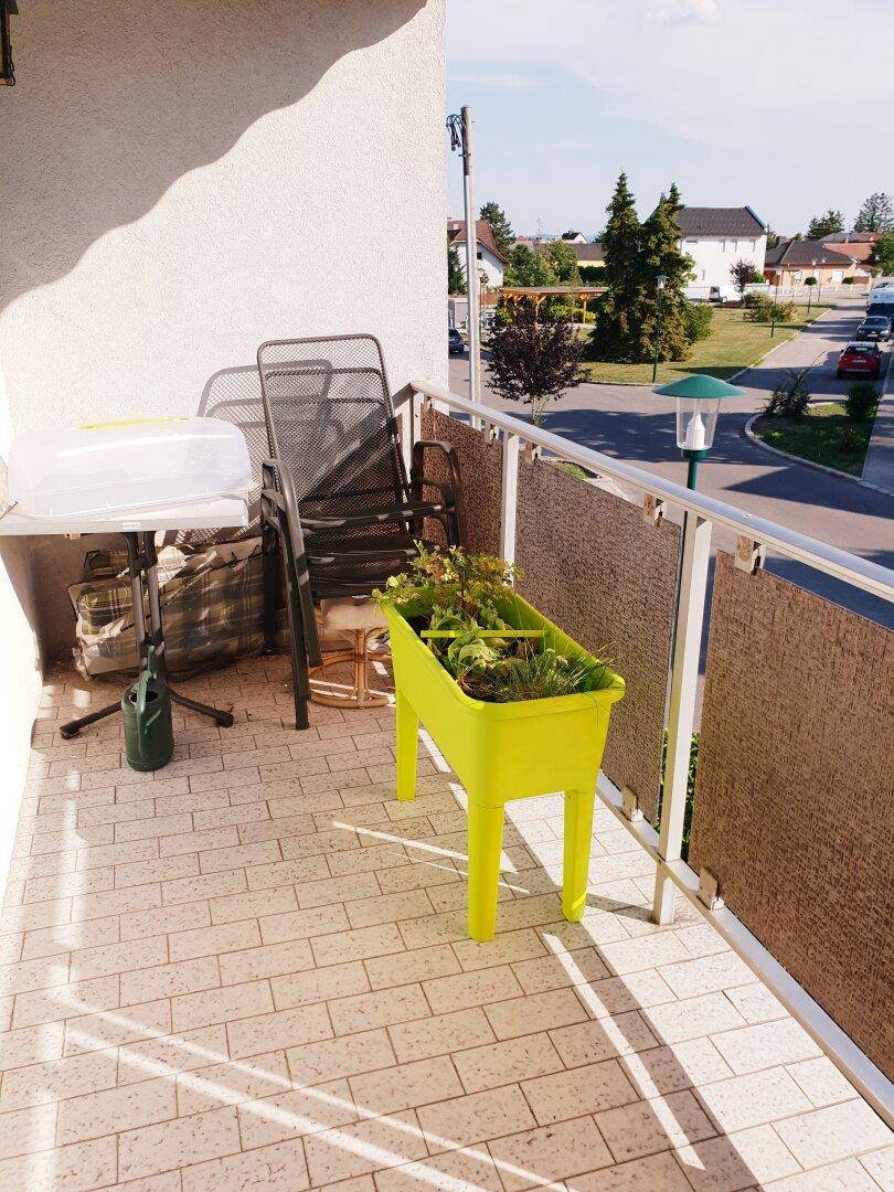 Sonniger Balkon mit Fliesenboden, Pflanzkübel und Blick auf die Umgebung.