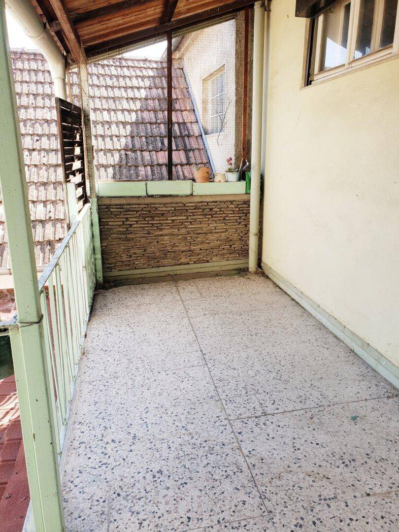 Überdachter Balkon mit Fliesenboden und Blick auf die umliegenden Ziegeldächer.