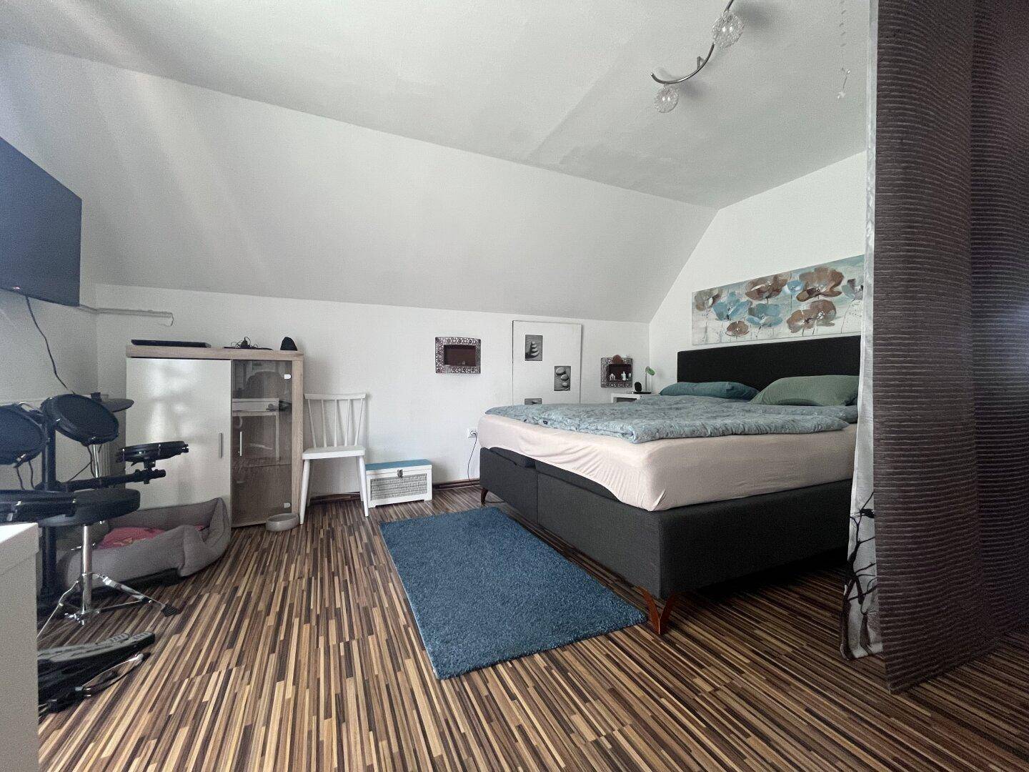 Gemütliches Schlafzimmer im Dachgeschoss mit Doppelbett, Teppich und Laminatboden.