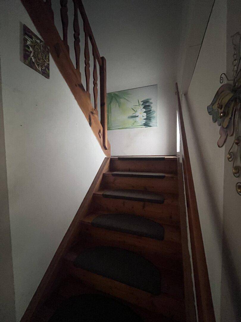 Rustikale Holztreppe mit Geländer verbindet die Stockwerke und führt nach oben.