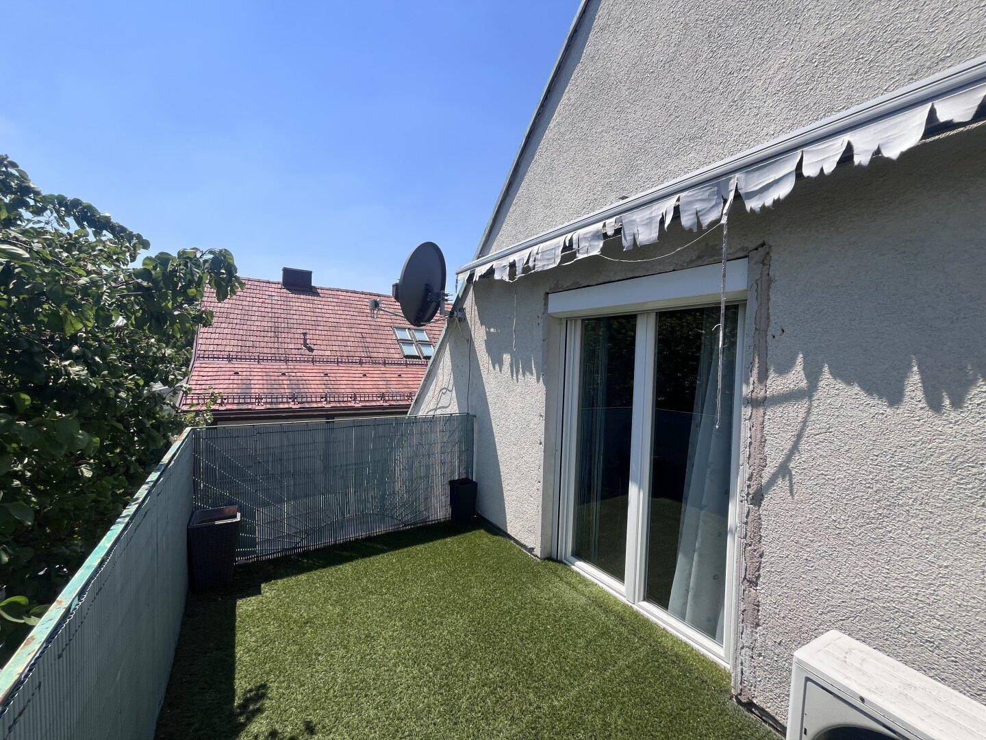 Balkon mit Kunstrasen und Blick auf die Nachbarschaft, ideal zum Entspannen im Freien.
