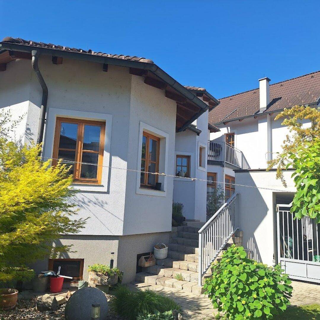Seitenansicht des Hauses mit gepflegtem Gartenbereich und Außentreppe.