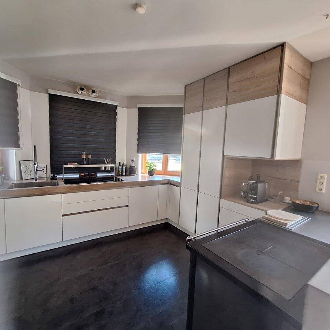 Helle Küche mit Holz- und Weißfronten, Induktionskochfeld und dunklem Holzboden.