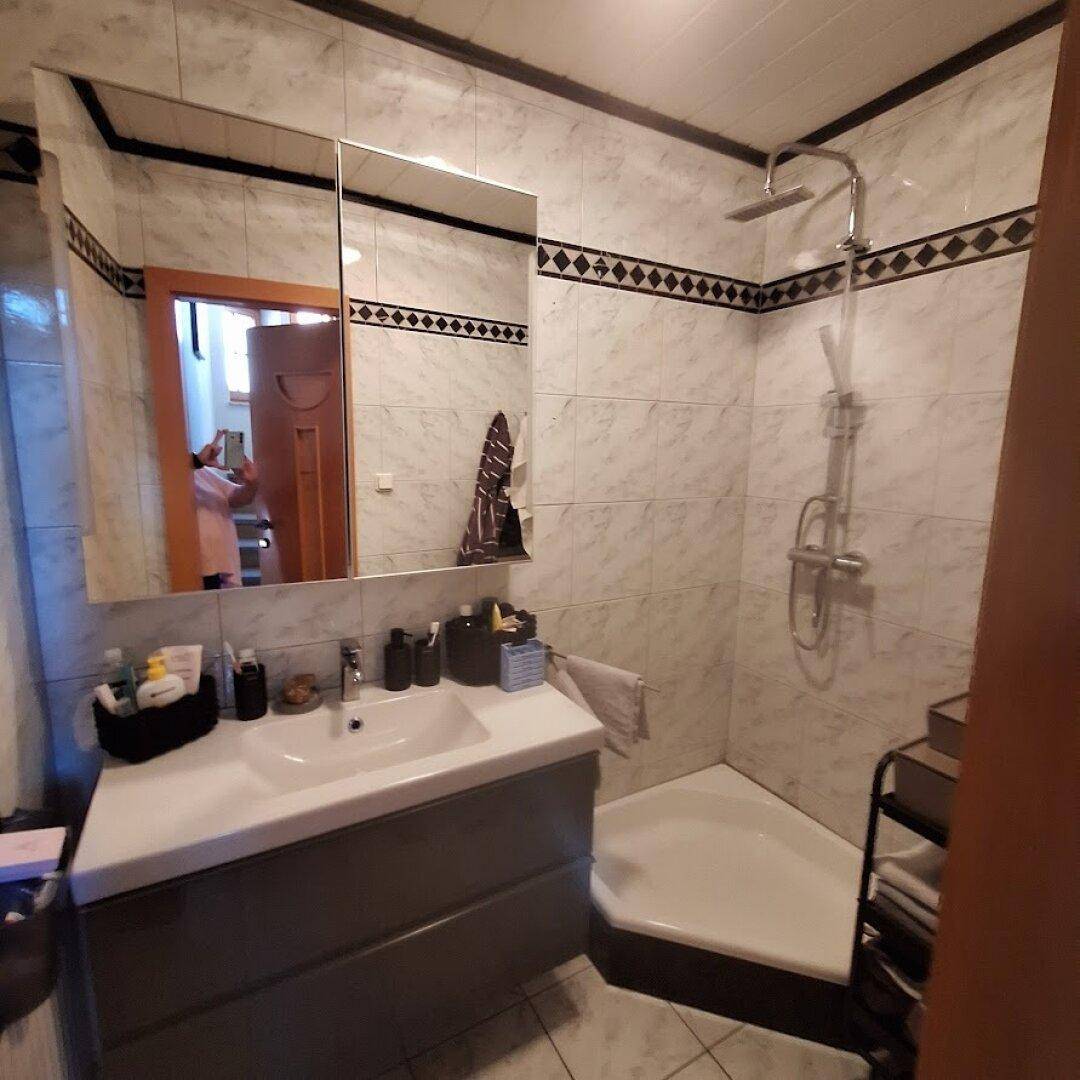 Badezimmer mit Duschkabine, Waschtischunterschrank und Spiegelschrank.